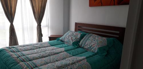 1 cama con edredón verde en un dormitorio en Apartamento Alturas del Elqui 417, en La Serena