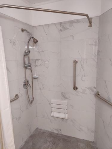 y baño con ducha y azulejos de mármol blanco. en Cadet Motel, en Cornwall-on-Hudson