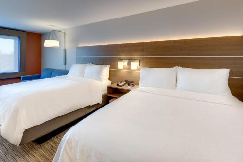 two beds in a hotel room with white sheets at Holiday Inn Express & Suites - Middletown - Goshen by IHG in Middletown