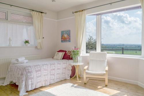 een slaapkamer met een bed, een tafel en een raam bij Healing Waters Sanctuary for Exclusive Private Hire and Self Catering Board, Vegetarian, Alcohol & Wifi Free Retreat in Glastonbury in Glastonbury