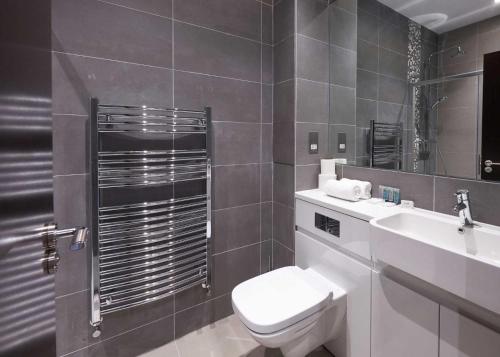 uma casa de banho com um WC, um lavatório e um espelho. em LuxuStay Serviced Apartments em Milton Keynes