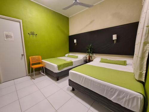 a room with two beds with green walls and a chair at Casa Mia in Puerto Escondido
