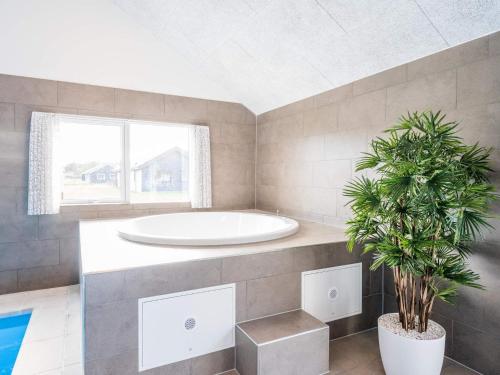 Un baño con bañera y una planta en maceta. en 26 person holiday home in Nørre Nebel, en Nørre Nebel