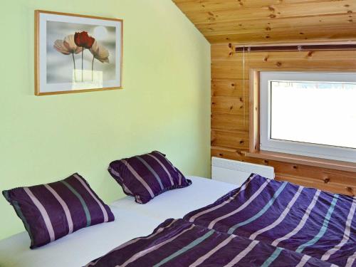 a bedroom with a bed with purple pillows and a window at 6 person holiday home in EIDSVÅG-By Traum in Rød