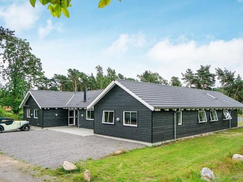 una casa negra con un coche aparcado delante de ella en 22 person holiday home in Nex, en Bedegård