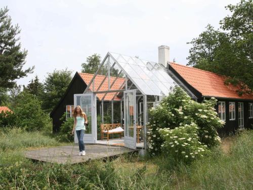 une femme debout devant une maison en verre dans l'établissement 10 person holiday home in Askeby, à Askeby