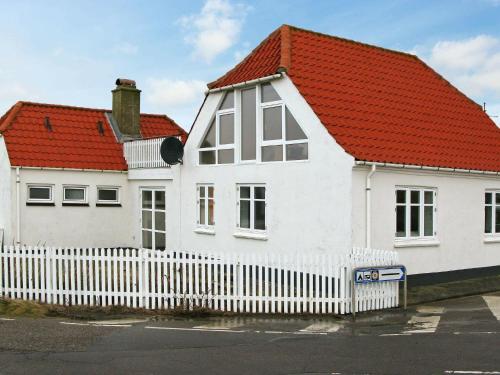 a white house with a red roof and a white fence at 4 person holiday home in Lemvig in Trans