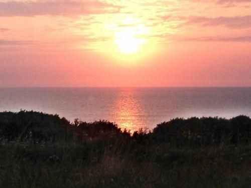 um pôr-do-sol sobre o oceano com o sol no céu em 4 person holiday home in Lemvig em Trans