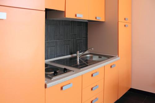 Una cocina con gabinetes naranjas y un fregadero. en Etna Holiday Home, en Nicolosi