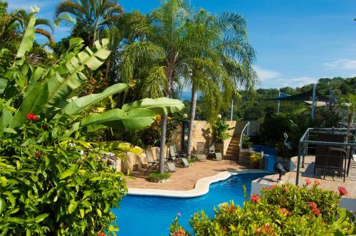 a pool in a resort with palm trees at Oceans Two Resort in Manuel Antonio