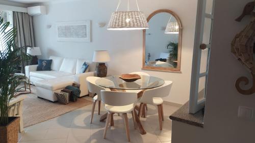 - un salon avec une table, des chaises et un canapé dans l'établissement Three Palms Apartment, à Ferragudo