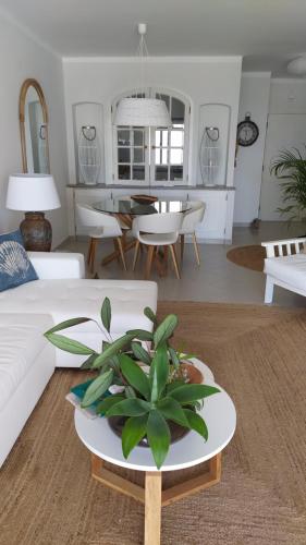 Three Palms Apartment في فيريغودو: غرفة معيشة بها أريكة بيضاء وطاولة بها نبات