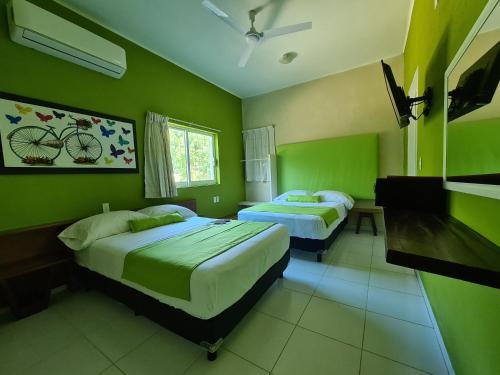 two beds in a room with green walls at Casa Mia in Puerto Escondido