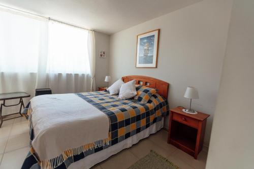 1 dormitorio con cama, mesa y ventana en Departamento Algarrobo Norte, en Algarrobo