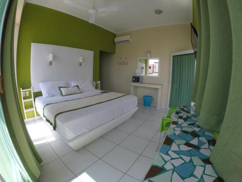 a bedroom with a white bed and a green wall at Casa Mia in Puerto Escondido