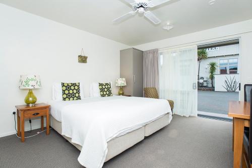 a bedroom with a large white bed and a television at AhiKaa Gisborne Motel in Gisborne