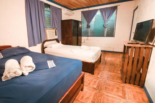 a bedroom with two beds and a flat screen tv at Villas Maria Luisa in Uvita