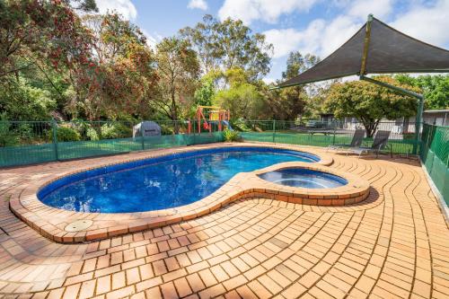 a swimming pool in a backyard with a playground at Castle Motel in Castlemaine