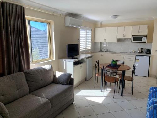 sala de estar con sofá, mesa y cocina en Bel Mondo Apartments, en Wollongong