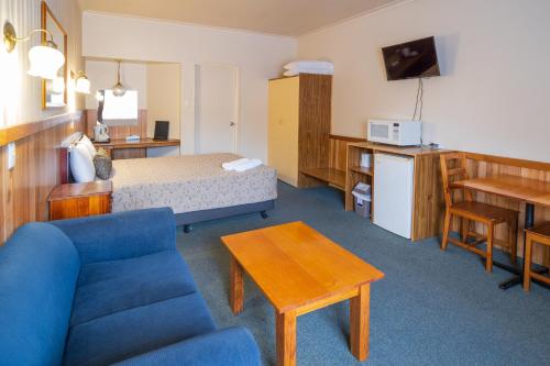 a hotel room with a blue couch and a bed at Castle Motel in Castlemaine