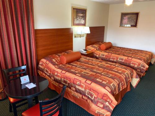 a hotel room with two beds and a table and chairs at Country Hearth Inn-Union City in Union City