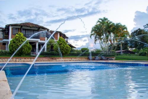 a pool with two fountains in front of a house at Finca Hotel Casa Nostra, villa Mariana in Quimbaya