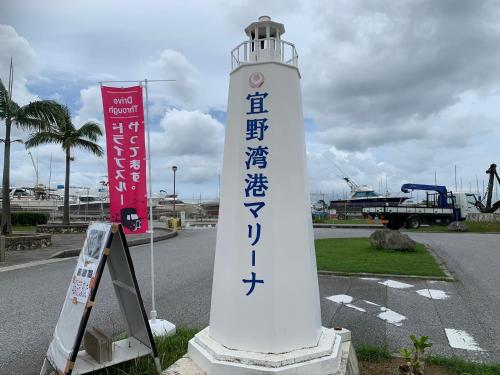 a white lighthouse with writing on it next to a street at Rizo Zaizen Hotel in Ginowan