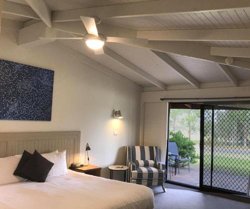 1 dormitorio con 1 cama con ventilador de techo y silla en Hunter Valley Resort, Hunter Farm Adventure Centre & 4 Pines at the Farm, en Pokolbin