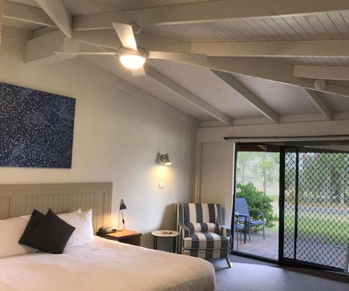 una camera con letto, ventilatore a soffitto e sedia di Hunter Valley Resort, Hunter Farm Adventure Centre & 4 Pines at the Farm a Pokolbin