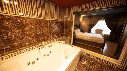 a bathroom with a tub and a bedroom with a bed at REFORM OTEl in Van