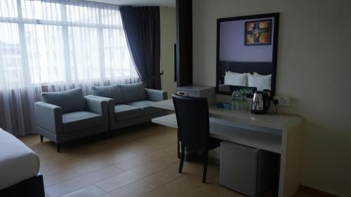 a hotel room with a bed and a desk and a couch at Be Boutique Hotel in Kluang