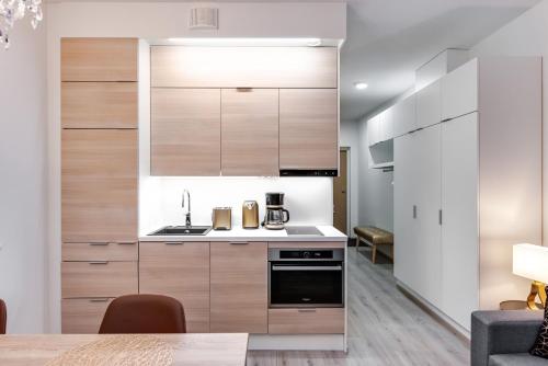a kitchen with wooden cabinets and a stove top oven at Trendy Homes Oulu Marski Apartments in Oulu