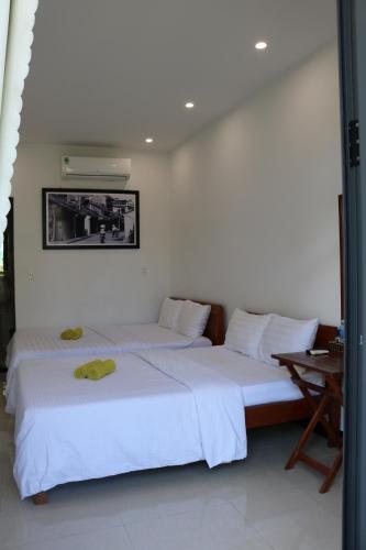 two beds in a room with white walls at Green garden house in Hoi An