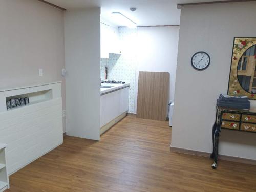a kitchen with white walls and a clock on a wall at HY Choi Hostel in Seogwipo