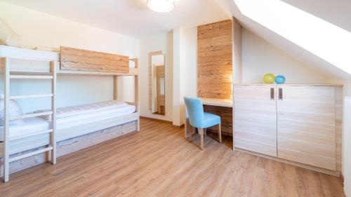 a bedroom with bunk beds and a blue chair at Pension Pirkdorfer See in Sankt Michael ob Bleiburg