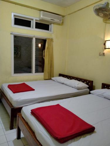 two beds in a room with a window at Prayogo Lama Family GH Prawirotaman in Yogyakarta