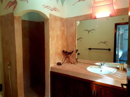 a bathroom with a sink and a mirror with birds on the wall at Boutique Hotel Nyumbani Tembo in Watamu