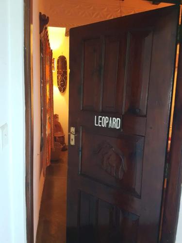 a wooden door with the word leopard written on it at Boutique Hotel Nyumbani Tembo in Watamu
