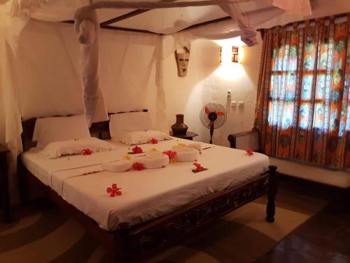 a bedroom with a bed with flowers on it at Boutique Hotel Nyumbani Tembo in Watamu