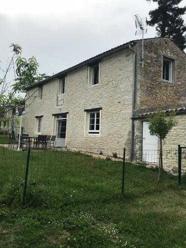 une ancienne maison en pierre avec une clôture devant elle dans l'établissement La grange du Logis du Plessis, à Chaniers
