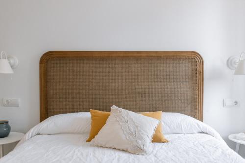- un lit avec des draps blancs et des oreillers jaunes dans l'établissement Ecoturisme Mas Ribas, à Palamós