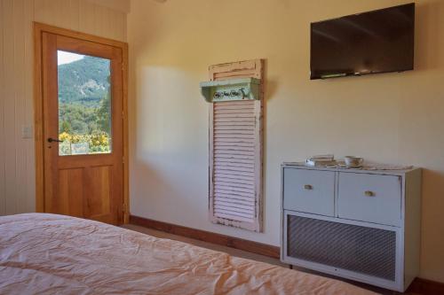 a bedroom with a bed and a television on the wall at Cinco Sentidos Hosteria in Villa Meliquina
