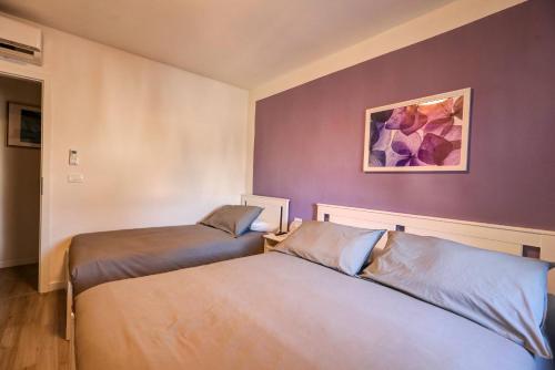 two beds in a room with purple walls at Affittacamere Scenario in Fogliano Redipúglia