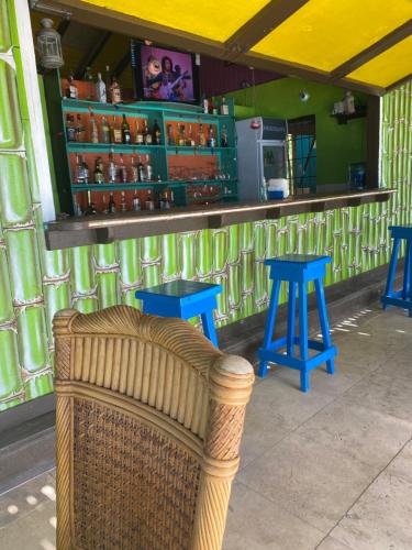 uma cadeira de vime em frente a um bar com bancos azuis em Orrie's Beach Bar and Hotel em Crab Hill