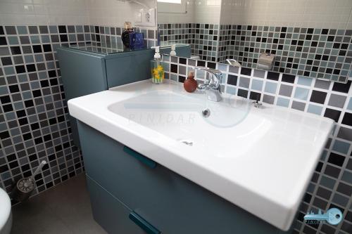 a bathroom with a white sink and black tiles at Piso centrico y moderno en Logroño Vivienda de uso Turistico in Logroño