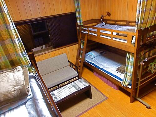 a room with three bunk beds and a couch at Aoshima Guesthouse Hooju in Miyazaki