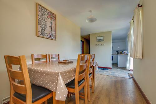 a dining room with a table and chairs and a kitchen at Anvil & Stable Cottages in Felbrigg