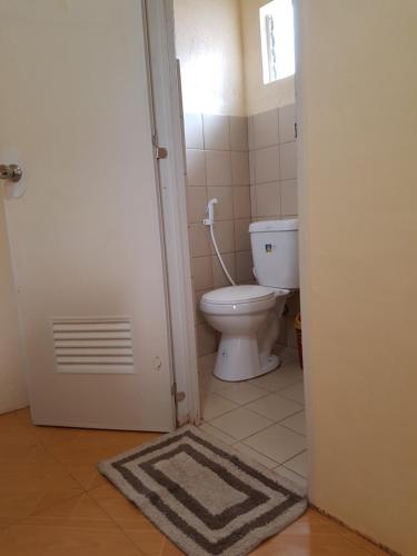 a bathroom with a toilet and a door with a rug at R&;S Restplace Resort in Matabungkay