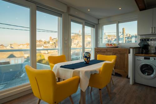 a kitchen with a table and chairs and windows at La tête Ault - Une expérience unique en bord de Mer in Ault