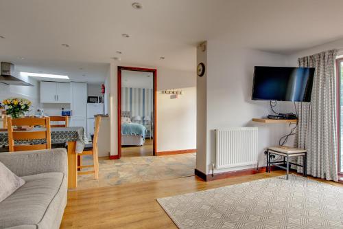 a living room with a couch and a tv on a wall at Anvil & Stable Cottages in Felbrigg